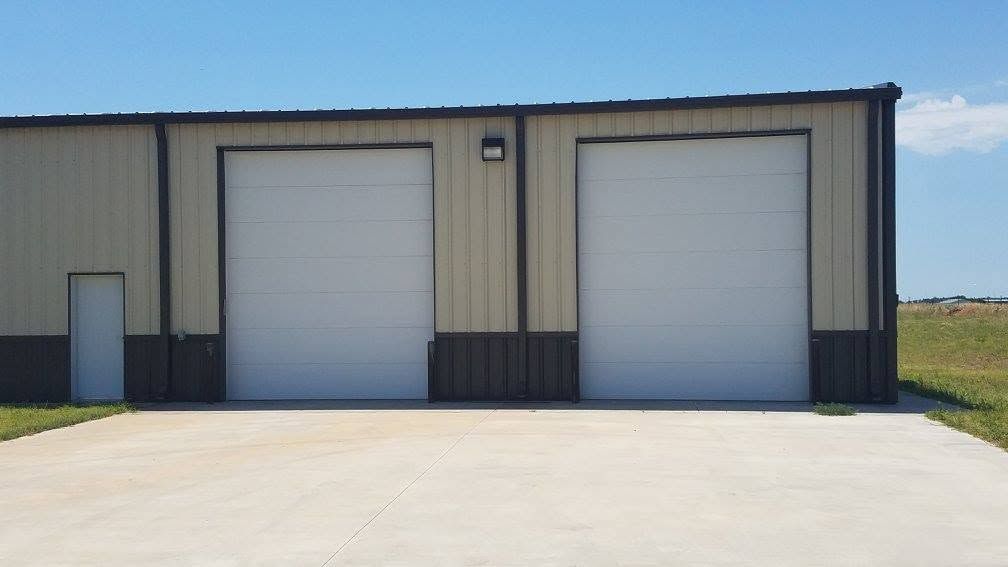 Two white commercial doors on a tan metal building