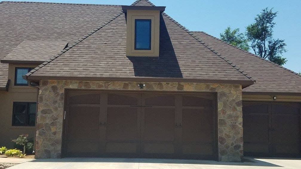 Brown carriage-style double garage door in a stone facade