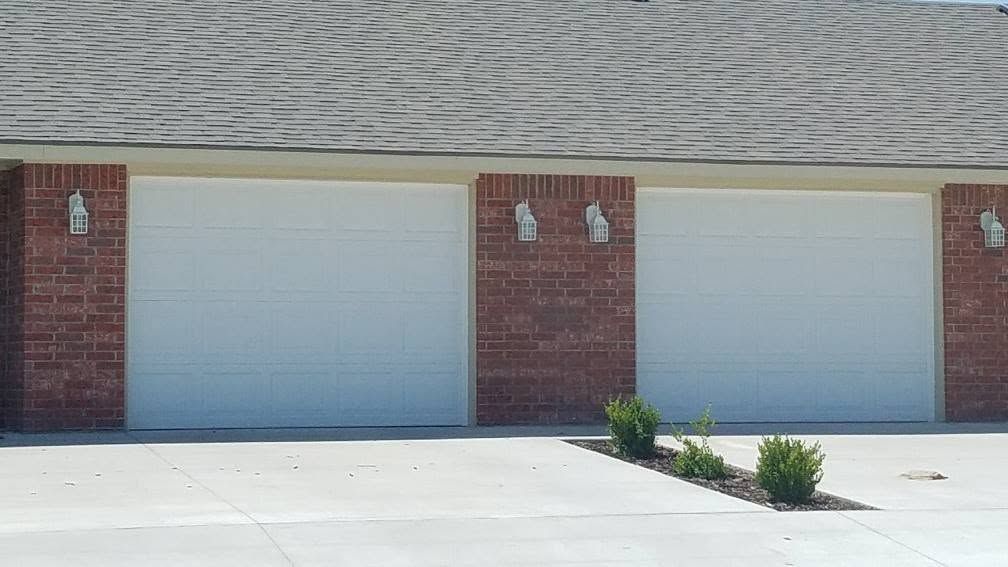 Two white raised-panel garage doors on a brick building